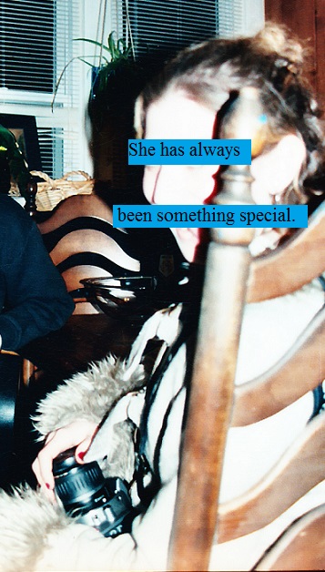 Blonde girl sitting at the table holding a camera looking