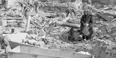 Elderly woman and a casket amid destruction